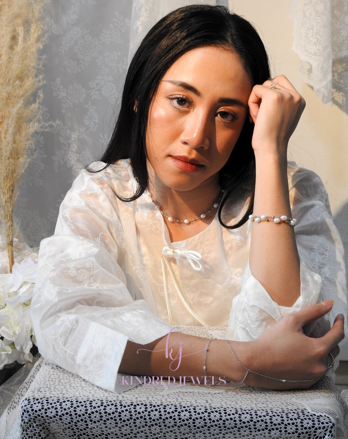 Woman in a white lace dress sitting outdoors with a blurred background