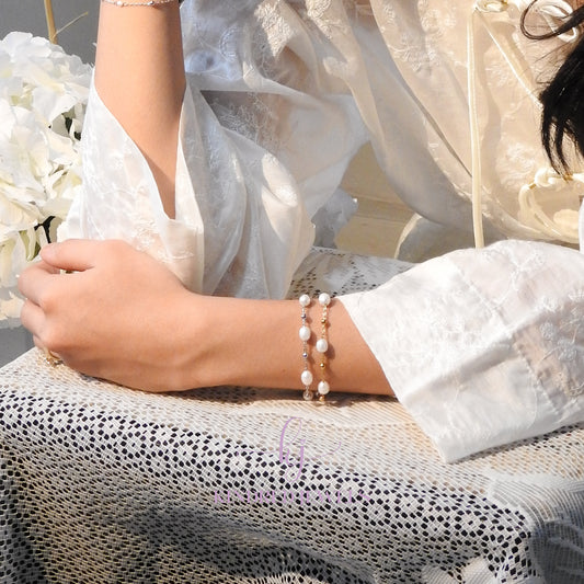 Person wearing a pearl bracelet with a blurred background