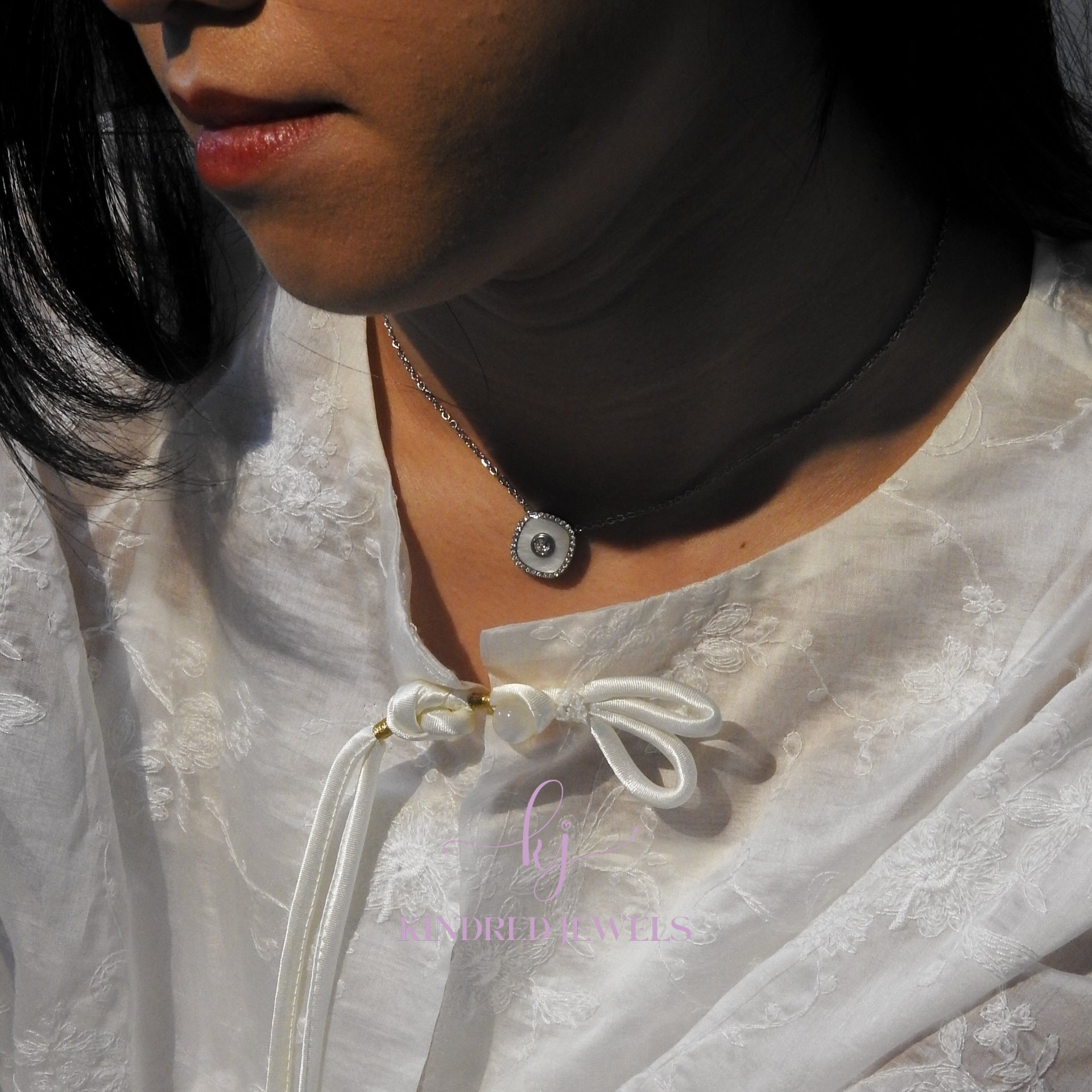 Close-up of a person wearing a white lace garment with a brand logo in the corner.