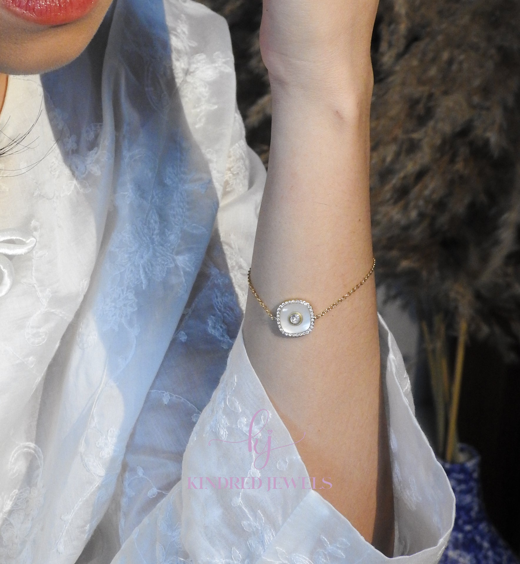 Close-up of a person wearing a delicate bracelet with a textured stone on a blurred background.