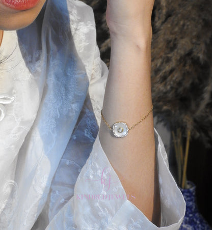 Close-up of a person wearing a delicate bracelet with a textured stone on a blurred background.