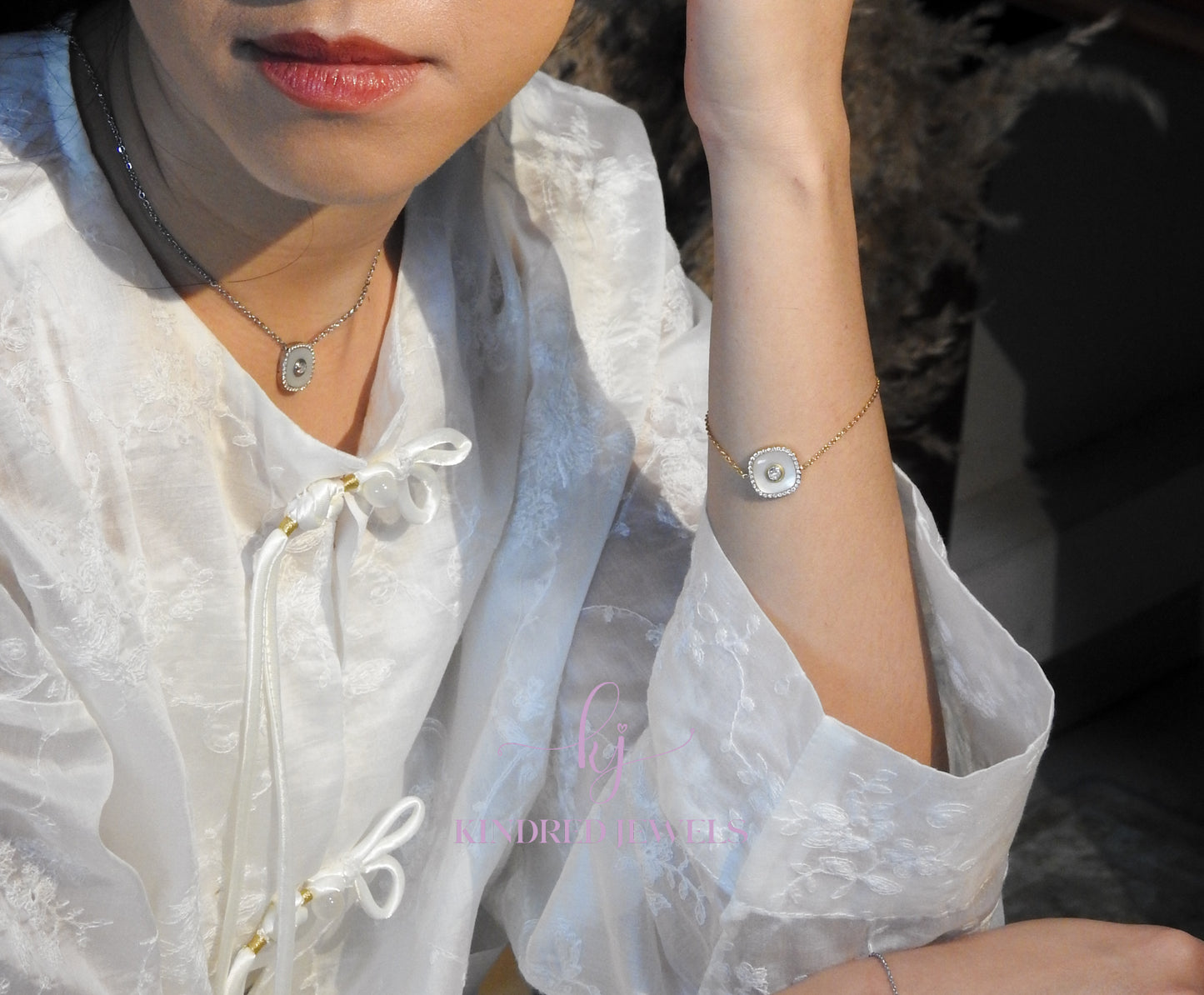 Person wearing a delicate necklace and bracelet with a blurred background