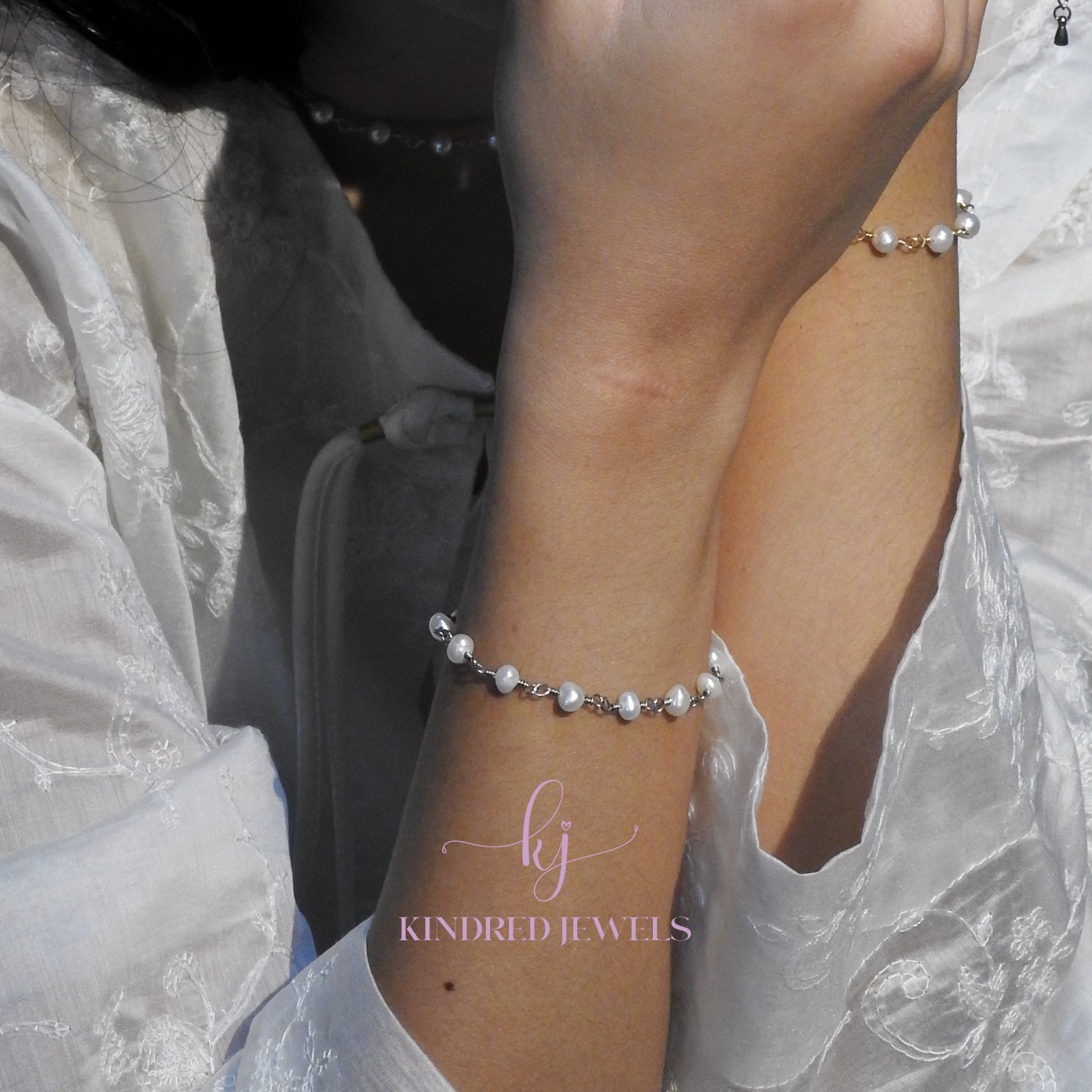Pearl bracelet on a wrist with 'KINDRED JEWELS' branding.