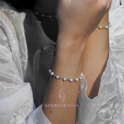 Pearl bracelet on a wrist with 'KINDRED JEWELS' branding.